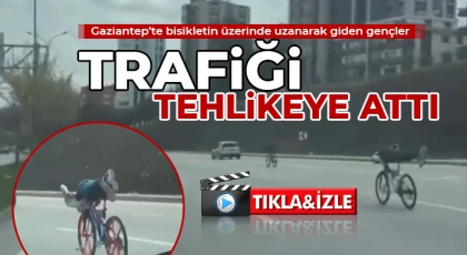  Bisikletin üzerinde uzanarak giden gençler trafiği tehlikeye attı